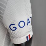 Close-up of white textured fabric with lace trim and a red, white, and blue stripe along the edge.
