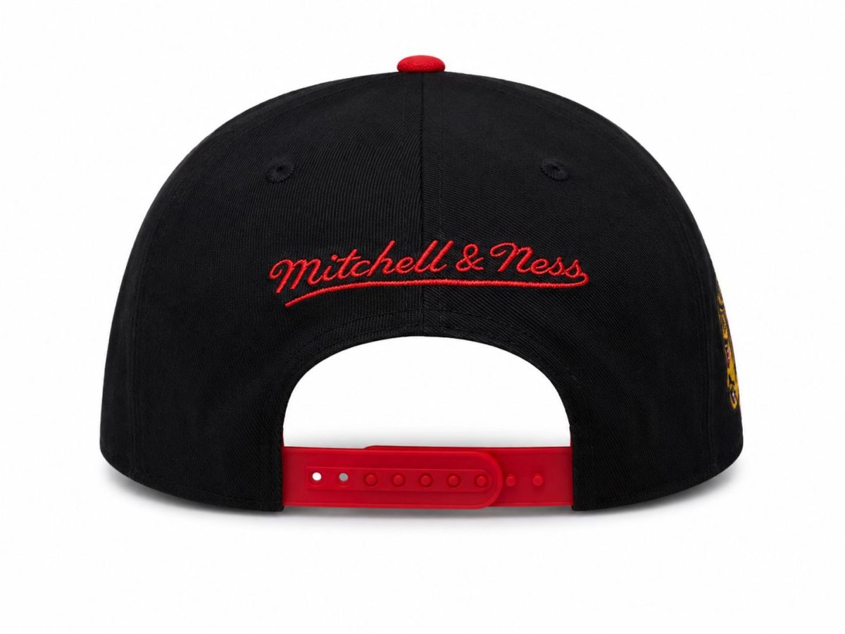 Back view of a black baseball cap with red embroidered 'Mitchell & Ness' lettering and a red adjustable snapback strap; white background.