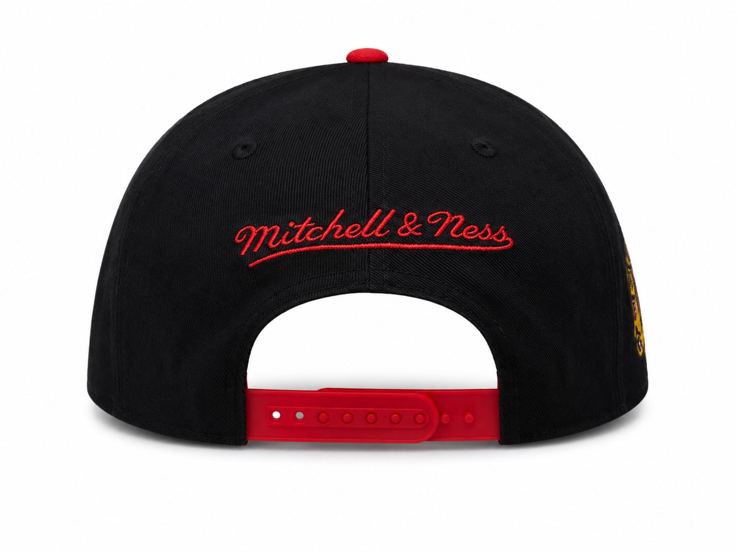 c3b58122-03cd-4316-882f-6415f1738017 | UAE SPORT STORE Back view of a black baseball cap with red embroidered 'Mitchell & Ness' lettering and a red adjustable snapback strap; white background.