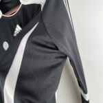 c3d3bca2_1ce62cd4-2362-4c66-a1e2-00d5b7d3d823 | UAE SPORT STORE Close-up of a black Adidas jacket with white piping and the Adidas logo visible on the chest area.