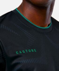 Close-up of a black athletic shirt with green trim at the neck and the CASTORE logo on the chest.