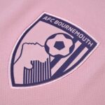 AFC Bournemouth club crest embroidered on pink fabric, showing a clenched fist and football motif inside a shield.