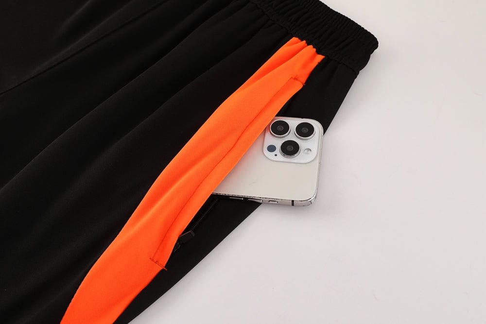 c4cd05a3 | UAE SPORT STORE Smartphone partially tucked into the pocket of black athletic pants with an orange side stripe on the leg.