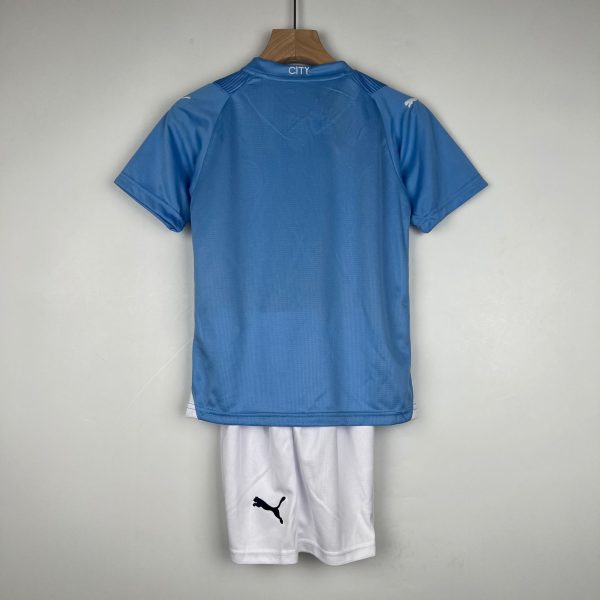 Blue sports jersey hanging on a wooden hanger with white shorts beneath; back collar reads CITY on the neck area.