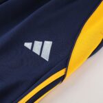 Close-up of navy fabric with a white embroidered three-bar design beside a yellow border.