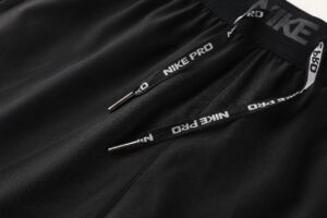 Close-up of black Nike Pro drawstrings with metal tips and branded elastic waistband in the background.