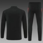 Black tracksuit set with jacket and matching pants shown against a gradient background; back view of the jacket and front view of the pants with subtle red side accents.