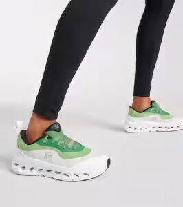 Person wearing lime green chunky sneakers stepping forward while wearing black leggings/leggings.