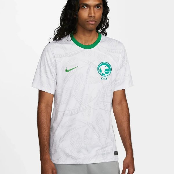Male model wearing a white patterned jersey with a green collar and a teal SAFF crest on the chest, standing against a light background.