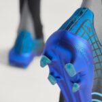 c6ef96bd-4a75-4558-9bf1-eefd35435d30 | UAE SPORT STORE Close-up of a blue athletic shoe with plastic studs on the sole, foreground focus on the cleats.