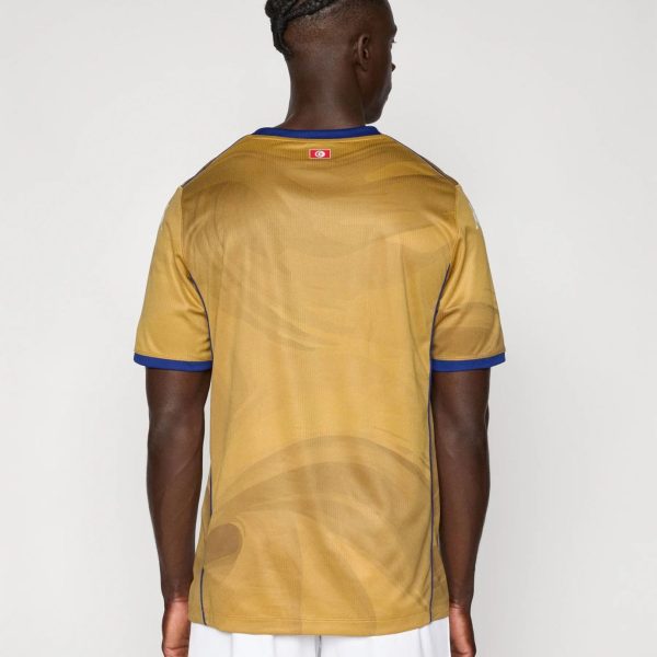 Back view of a person wearing a gold athletic jersey with blue trim and a small flag patch on the upper back, with white shorts below.