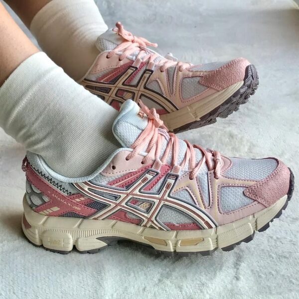 c75d3774-1940-4ff2-8053-14a2dd77e432 | UAE SPORT STORE Pastel pink and gray ASICS running shoes with pink laces, worn with white socks, seen from the side.