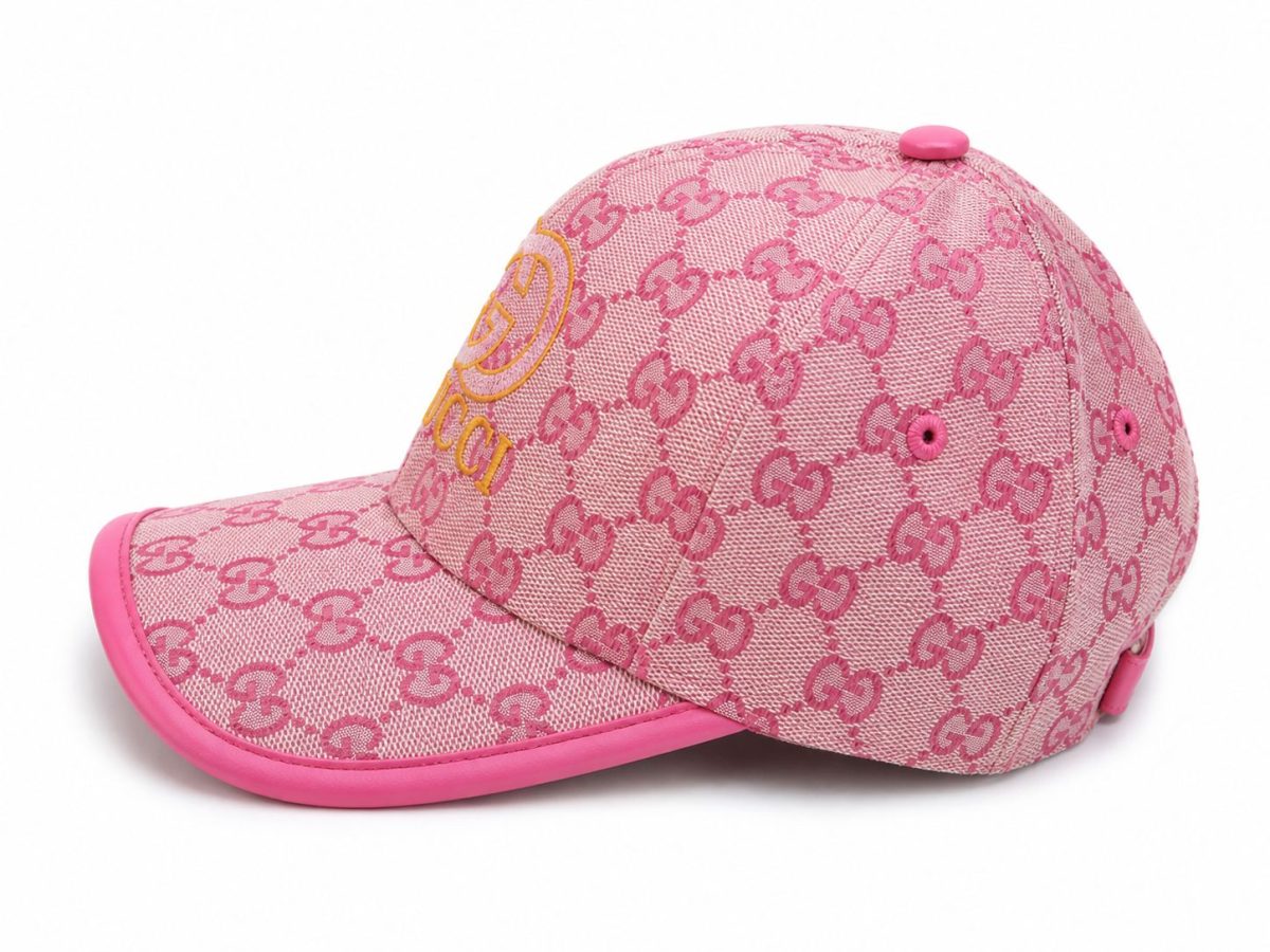 Pink baseball cap featuring Gucci's repeating GG pattern in pink, with a yellow Gucci logo on the front and a pink brim.