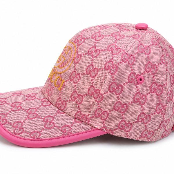 Pink baseball cap featuring Gucci's repeating GG pattern in pink, with a yellow Gucci logo on the front and a pink brim.