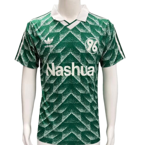 Green chevron-patterned soccer jersey on a mannequin, with a white collar, Adidas logo and club crest, and 'Nashua' sponsor text on the chest.