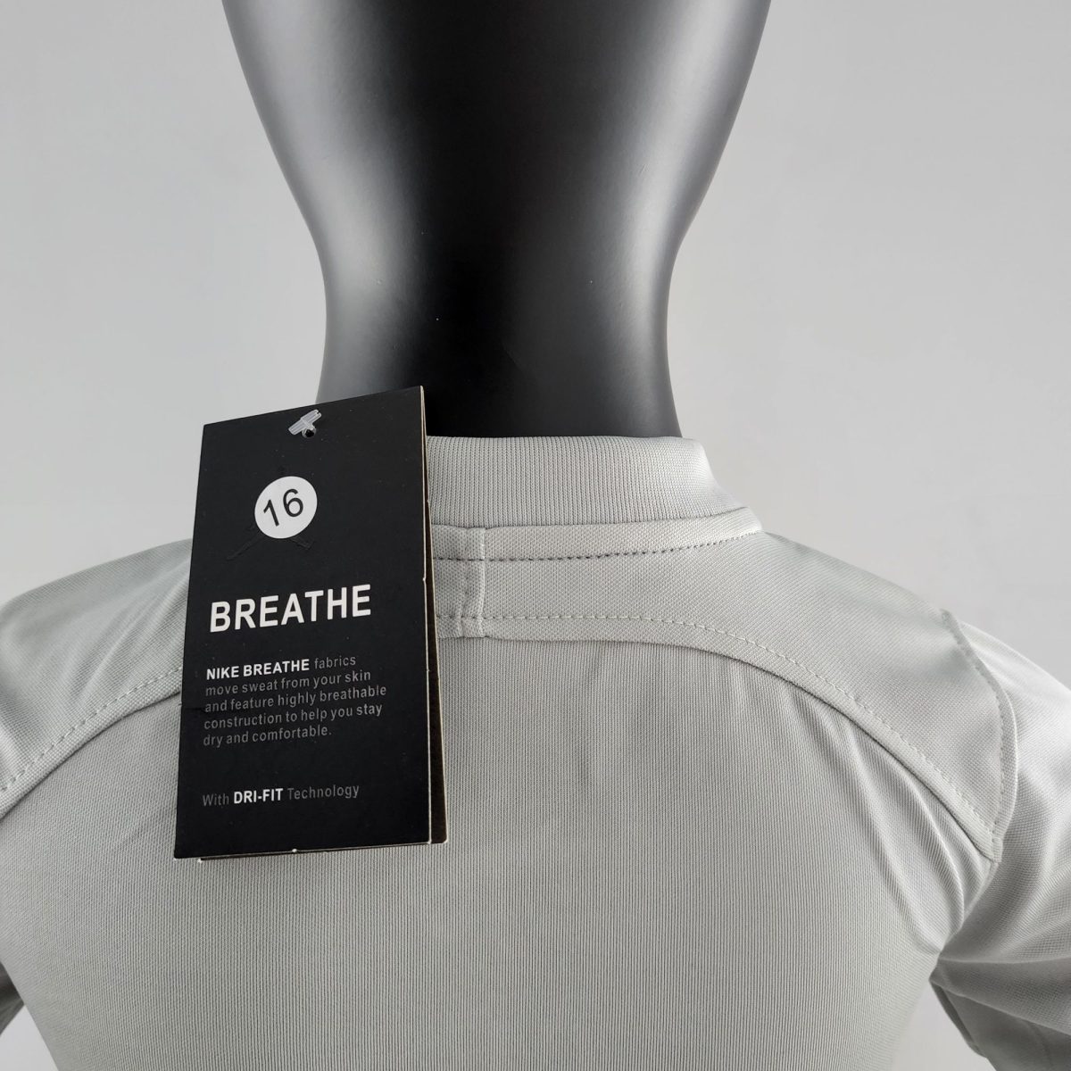 Black mannequin torso wearing a light gray shirt with a Nike BREATHE tag attached, highlighting DRI-FIT fabric details.