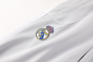 Close-up of the Real Madrid crest embroidered on light gray fabric (likely a jersey or sports apparel).