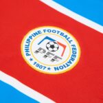 c7eebec6-647f-4884-a797-b6bb39784c18 | UAE SPORT STORE Close-up of the Philippine Football Federation emblem on red fabric, with blue and white accents and the year 1907.