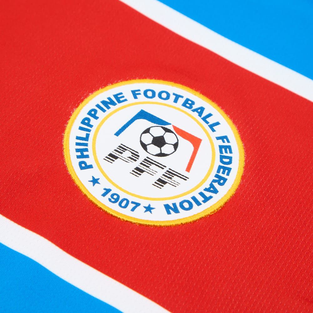 c7eebec6-647f-4884-a797-b6bb39784c18 | UAE SPORT STORE Close-up of the Philippine Football Federation emblem on red fabric, with blue and white accents and the year 1907.