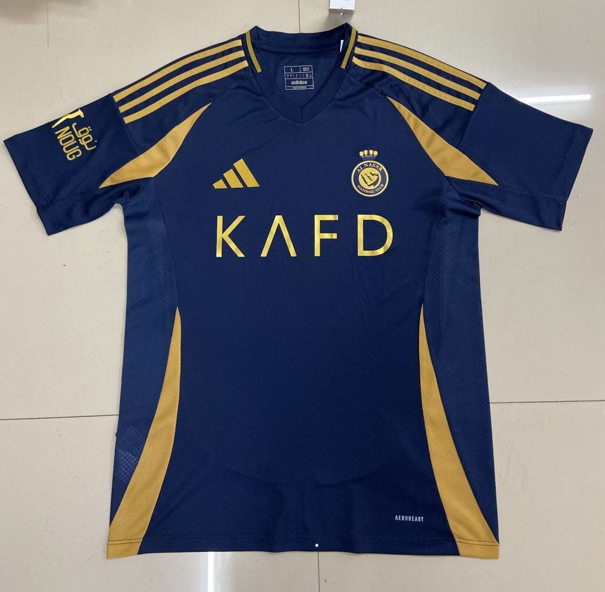 Navy blue Adidas soccer jersey with gold accents, including three gold stripes on the shoulders, a gold crest on the chest, and the letters KAFD across the front.