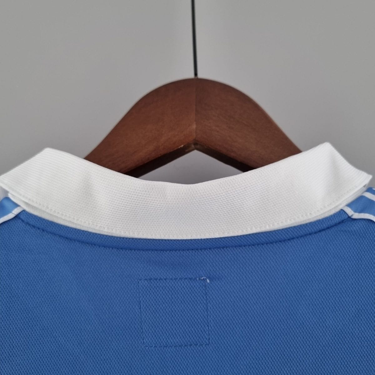 Close-up of a blue shirt with a white collar, hanging on a wooden hanger