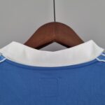 c83123bd_e87aba70-64e8-41f0-8f3b-ade8cd819ab7 | UAE SPORT STORE Close-up of a blue shirt with a white collar, hanging on a wooden hanger