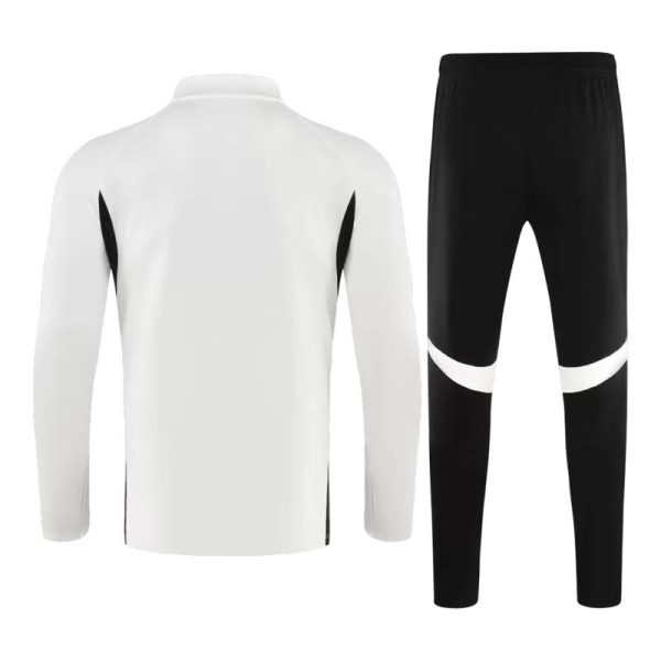 White long-sleeve athletic jacket with black side panels, paired with black track pants that have a white curved stripe across the thighs (sportswear set).