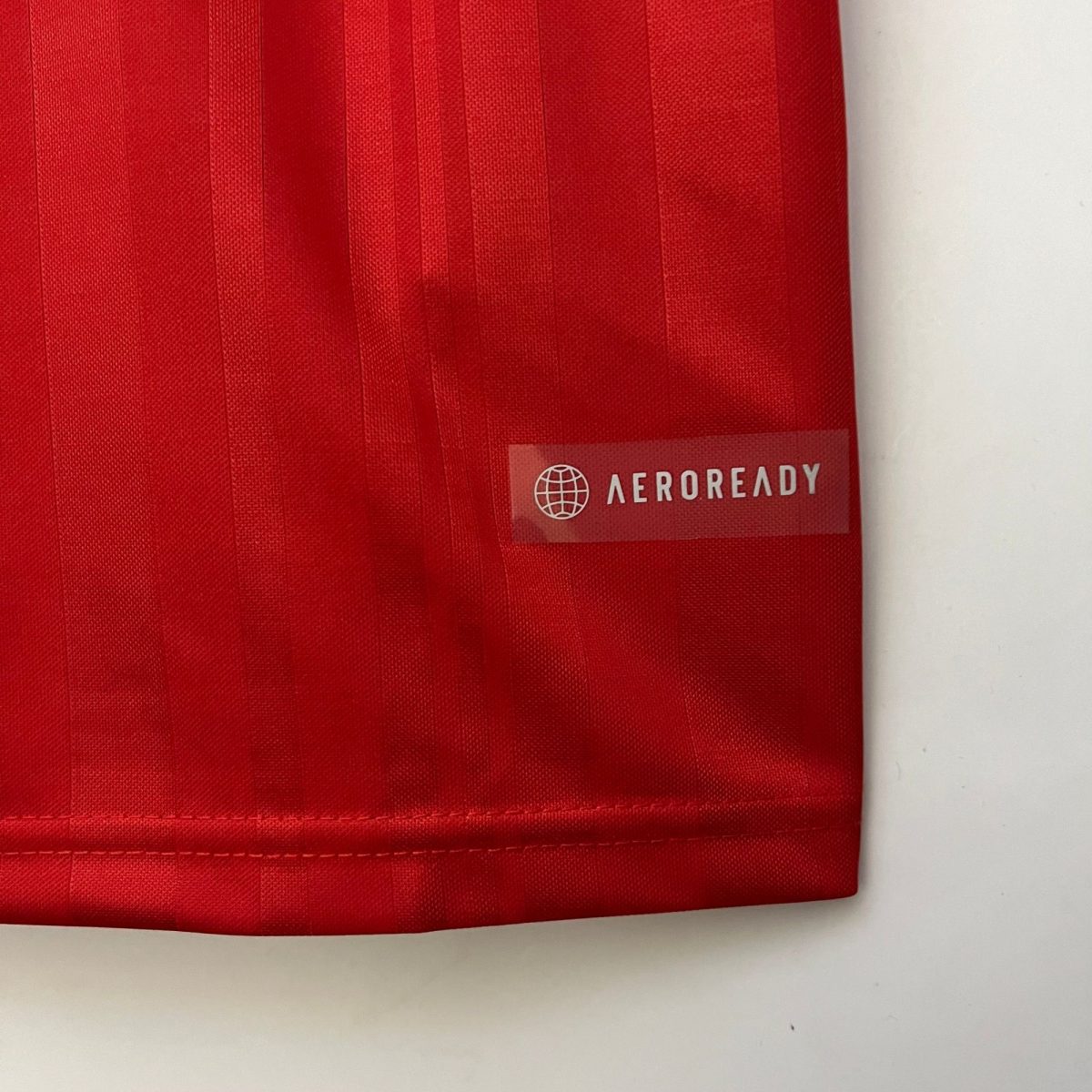 Close-up of red fabric with visible vertical seams and a watermark tag reading 'AEROREADY' on the lower right.