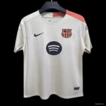 White FC Barcelona jersey on hanger with Nike swoosh and Spotify sponsor logo; features orange shoulder detail.