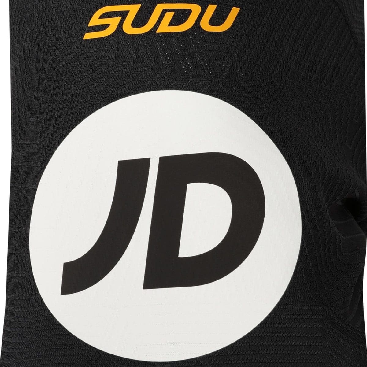 Close-up of black patterned fabric with an orange 'SDU' logo above a large white circle containing a black letter 'D'. The image shows branding detail on a textile item.