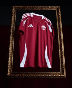 Maroon Adidas sports jersey framed in an ornate gold frame, white stripes on shoulders, QFA emblem on chest.