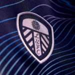 Close-up of the LUFC shield crest embroidered on a blue jersey.