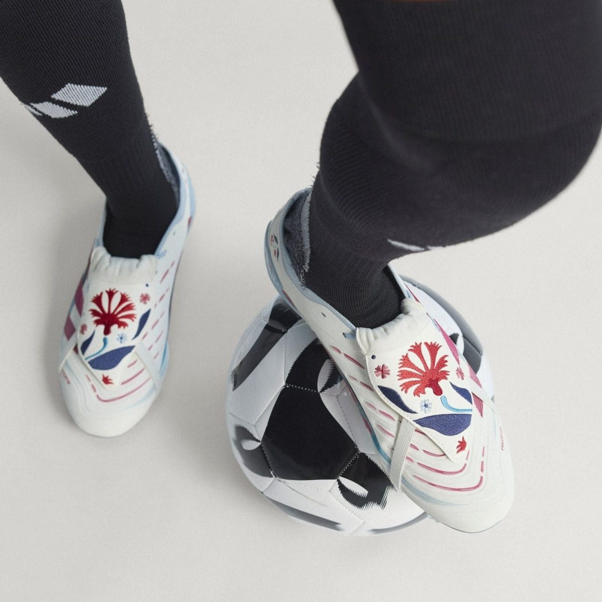 Close-up of colorful patterned soccer cleats and black socks resting on a white soccer ball.