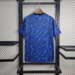 Blue short-sleeve shirt with a wavy blue pattern on a wooden hanger in a retail display rack.
