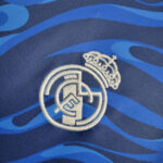 Embroidered Real Madrid crest on a blue patterned fabric.
