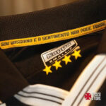 Close-up of a black garment with a Kappa label, a yellow slogan band, five gold stars beneath, and a Visco Store watermark in the corner.