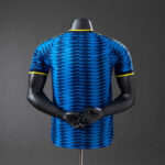 camiseta-colombia-segunda-equipacion-version-jugador-mundial-2026-parte-trasera | UAE SPORT STORE Back view of a blue athletic jersey with a zigzag pattern and yellow trim on sleeves and collar, displayed on a mannequin torso.