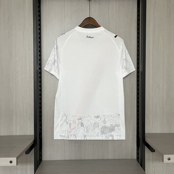 White short-sleeve T-shirt on a hanger in a closet; light gray pattern on sleeves and bottom pocket; 'Kidsuper' logo at the back of the neck.