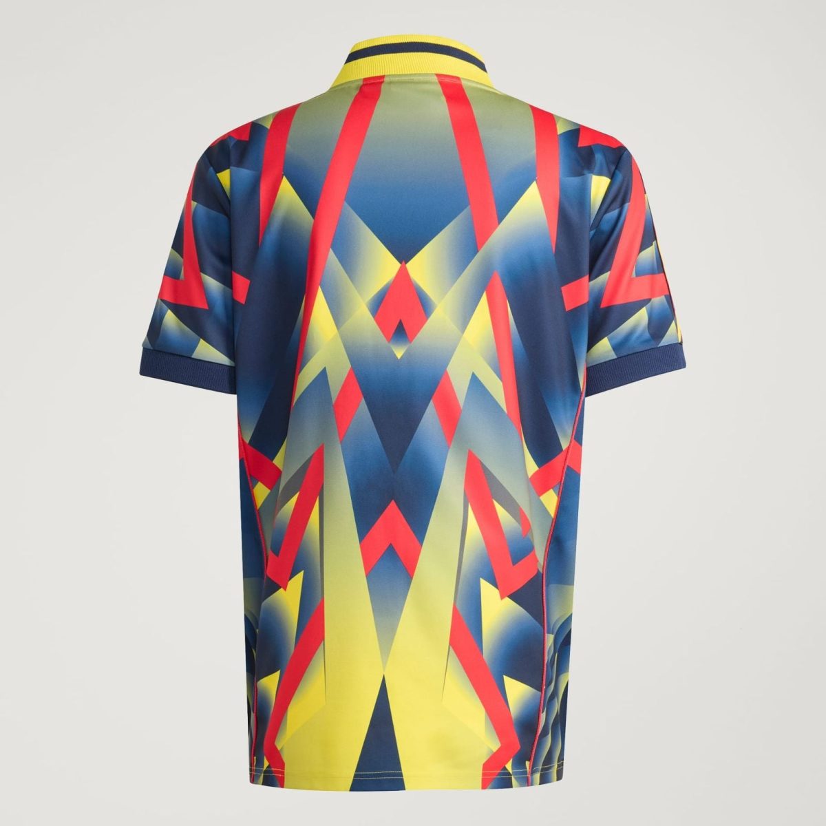 Back view of a short-sleeve polo shirt with a bold abstract geometric pattern in red, yellow, blue, and navy, featuring a striped yellow collar with a blue stripe.