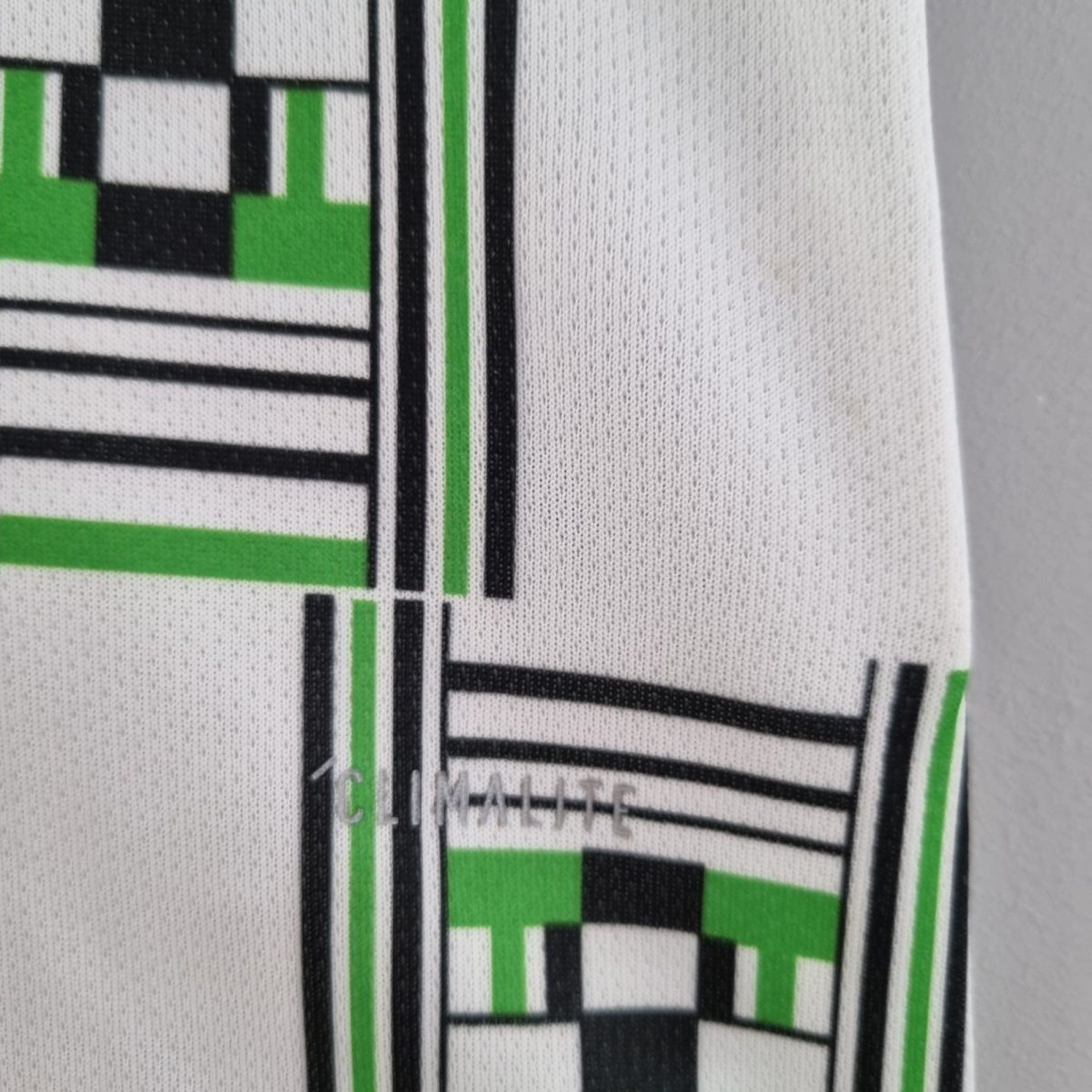 Close-up of white fabric featuring a bold black and green geometric print on textured material.