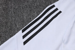 White sports sleeve on a gray carpet with three black stripes along the shoulder area (Adidas-style).