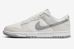 White low-top Nike sneaker with a gray swoosh, perforated toe, and gray sole (side view).