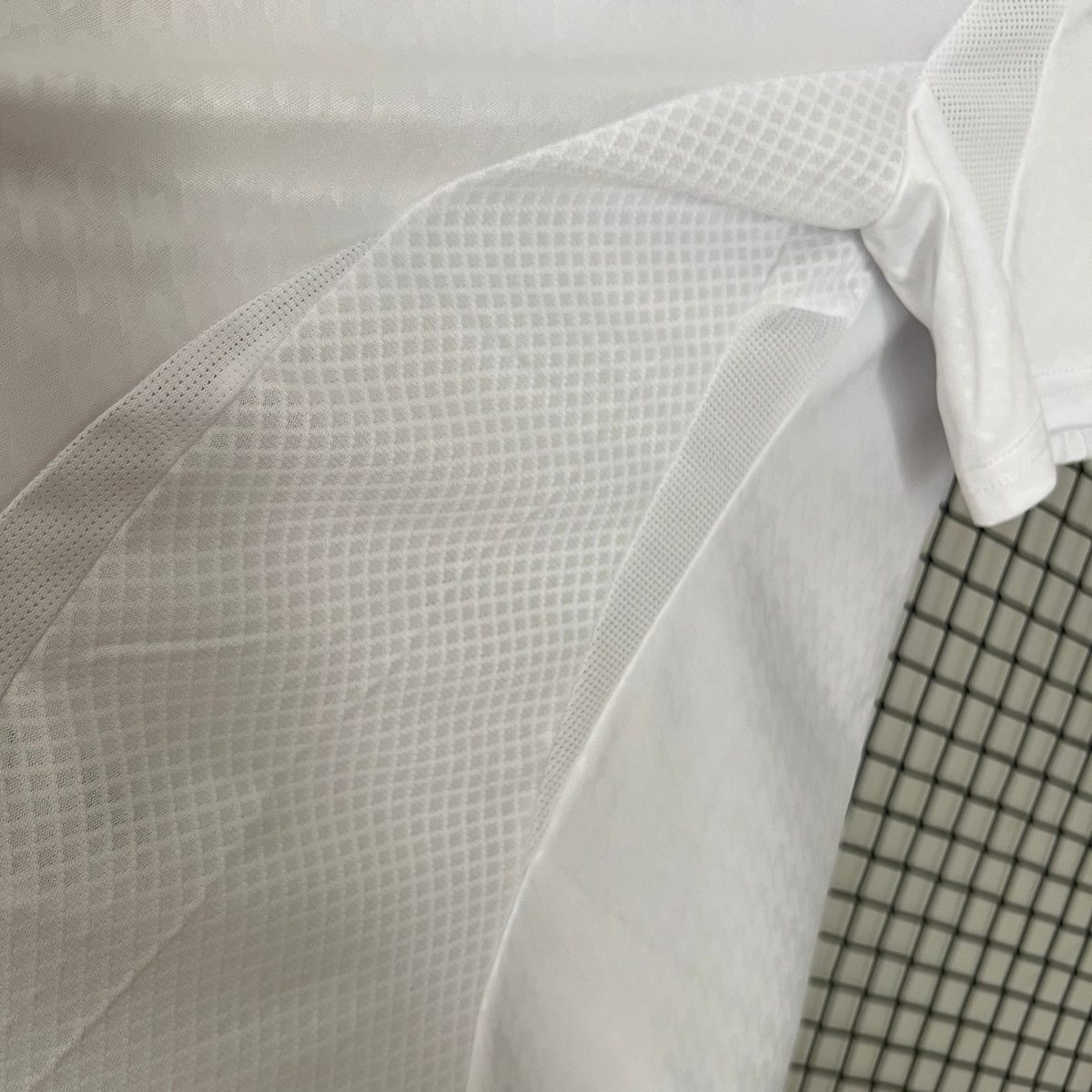 Close-up of layered white fabrics with varying textures and a rolled sleeve on the right.