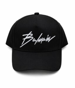 Black six-panel baseball cap with white embroidered Balmain logo on the front surface.
