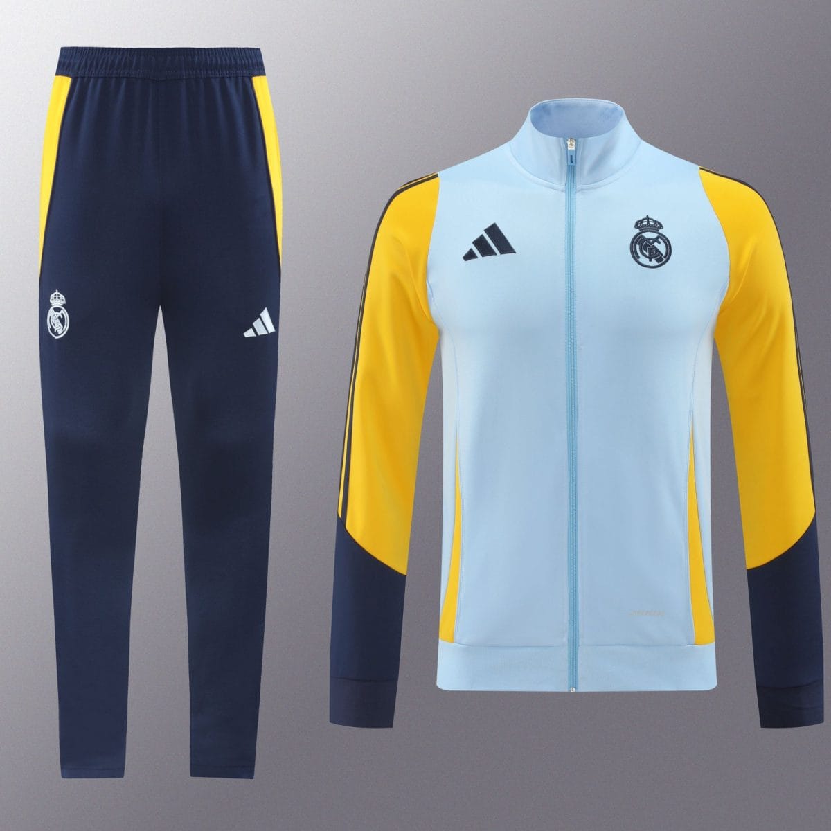 Real Madrid training outfit: navy track pants with yellow side panels and crest, plus a light-blue jacket with yellow sleeves and crest.