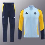 Real Madrid training outfit: navy track pants with yellow side panels and crest, plus a light-blue jacket with yellow sleeves and crest.
