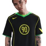Young man wearing a black sports jersey with neon green trim and the number 90 on the chest.