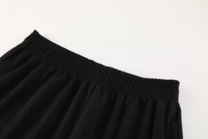 cef0b1cb | UAE SPORT STORE Close-up of black elastic waistband on smooth black fabric, showing shirred stitching and gathers.