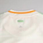 celtic-men-s-2025-26-third-shirt-1180888102 | UAE SPORT STORE Back of a white Celtic football jersey with an orange trim on the collar and a green CELTIC label.