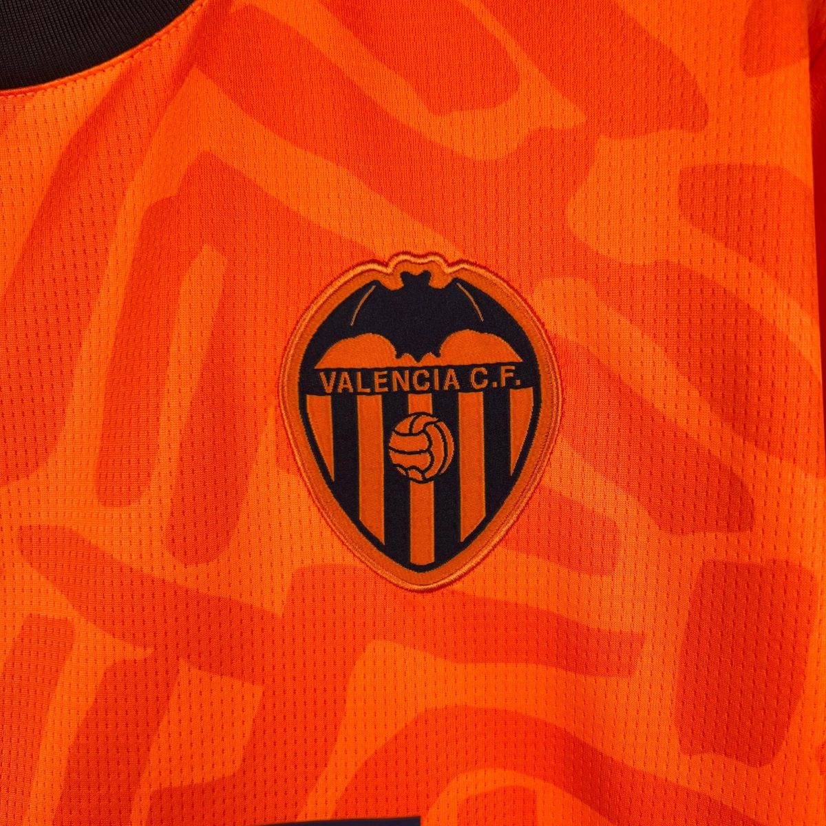 Close-up of orange Valencia CF jersey fabric with partial crest and text Valencia C.F.